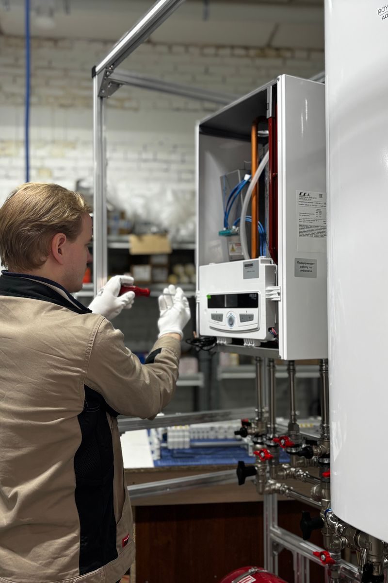HVAC technician servicing a heating system beside a warm brick wall